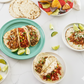 Plates of tacos with sides on a white table